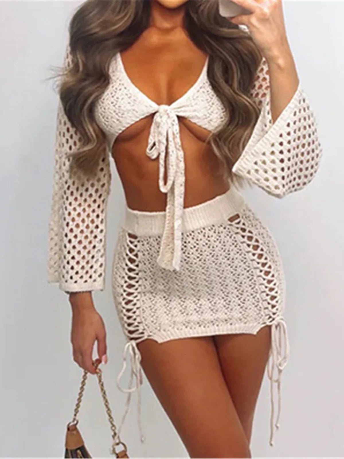 Two-piece outfit with hollow-out crochet design, long sleeve crop top with tie-up, mini skirt, solid pattern, polyester, beachwear or casual wear for women.